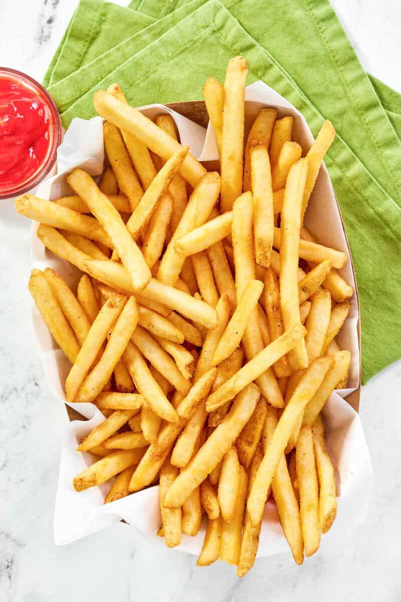 Copycat Wingstop seasoned French fries in a parchment paper lined paper serving basket.