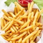 Copycat Wingstop seasoned French fries and a small cup of ketchup.