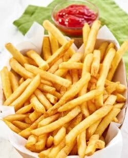 Copycat Wingstop seasoned French fries and a small cup of ketchup.
