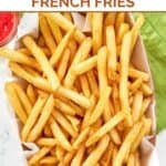 Homemade Wingstop seasoned French fries, a small cup of ketchup, and a cloth napkin.