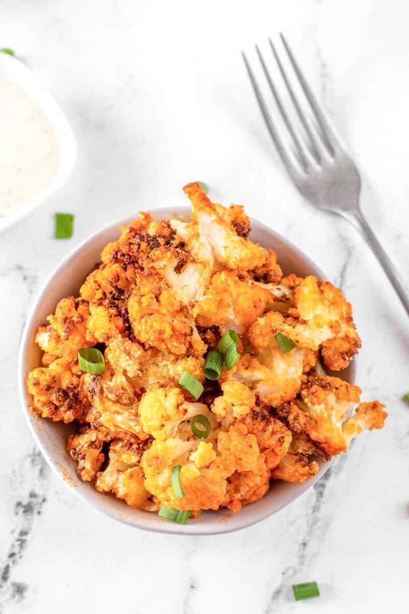 Air fryer buffalo cauliflower and a fork on a marble surface.