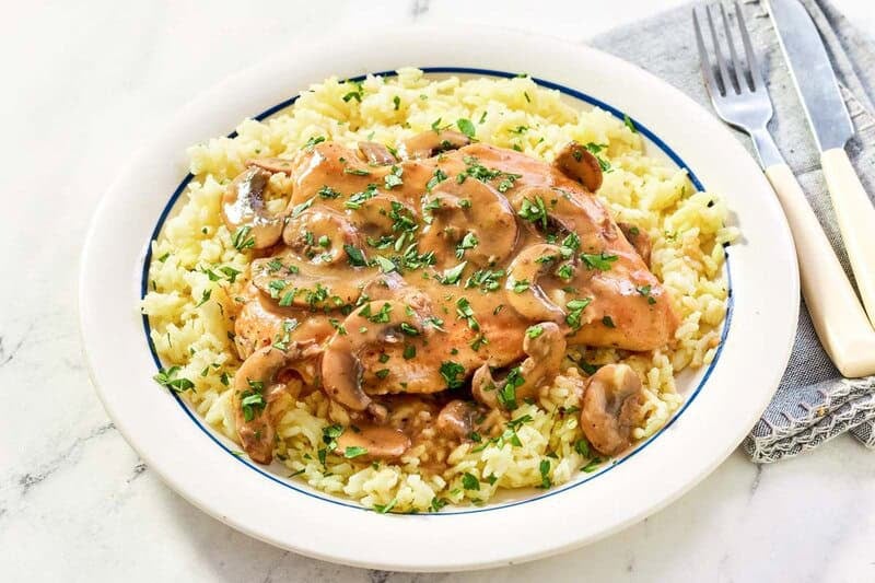 Copycat Cracker Barrel chicken and rice with gravy and a fork and knife on a napkin.