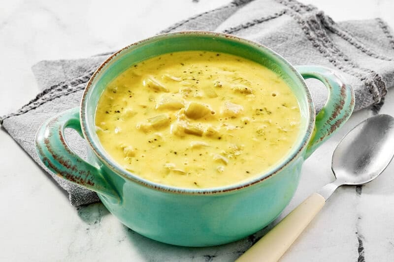 Copycat Jason's Deli broccoli cheese soup, a spoon, and a cloth napkin.