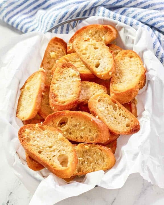Homemade Jason's Deli garlic toast in a serving basket on a marble surface.