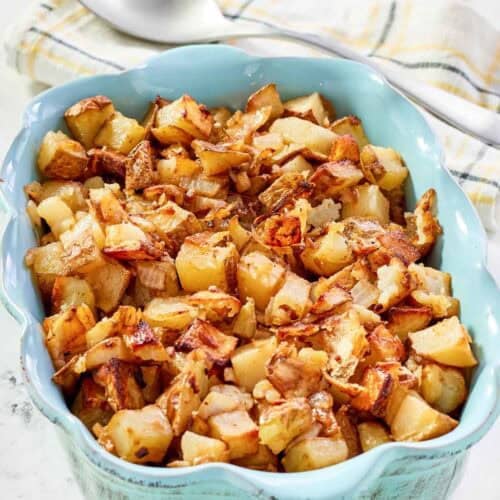 Lipton onion soup mix roasted potatoes in a serving dish and a serving spoon behind it.