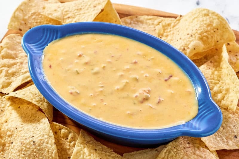 Spicy Rotel dip served with tortilla chips on a wood platter.