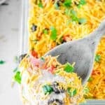 Ultimate 7 layer dip on a wooden spoon over the dip in a glass dish.