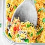 Ultimate 7 layer dip in a glass dish and a wooden spoon lifting some out of it.