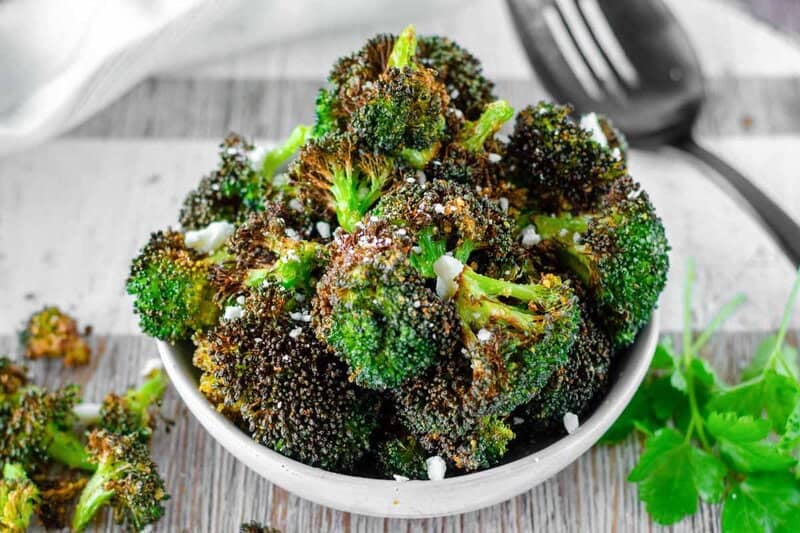 Air fryer broccoli in a bowl on a wood surface.