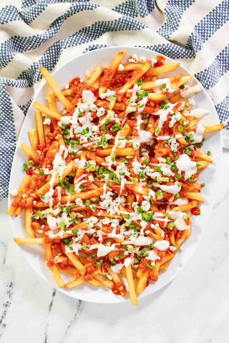 Buffalo fries on an oval platter and a kitchen towel next to it.