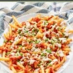 A platter of homemade buffalo fries and a kitchen towel by it.