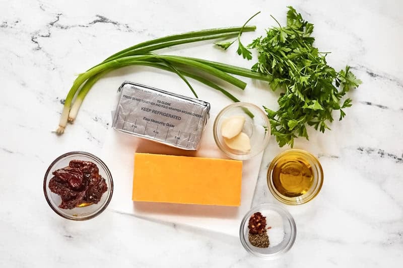 Cream cheese, cheddar cheese, sundried tomatoes, garlic, parsley, green onions, oil, and seasonings.