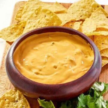 Green chile queso dip, tortilla chips, and fresh cilantro on a platter.