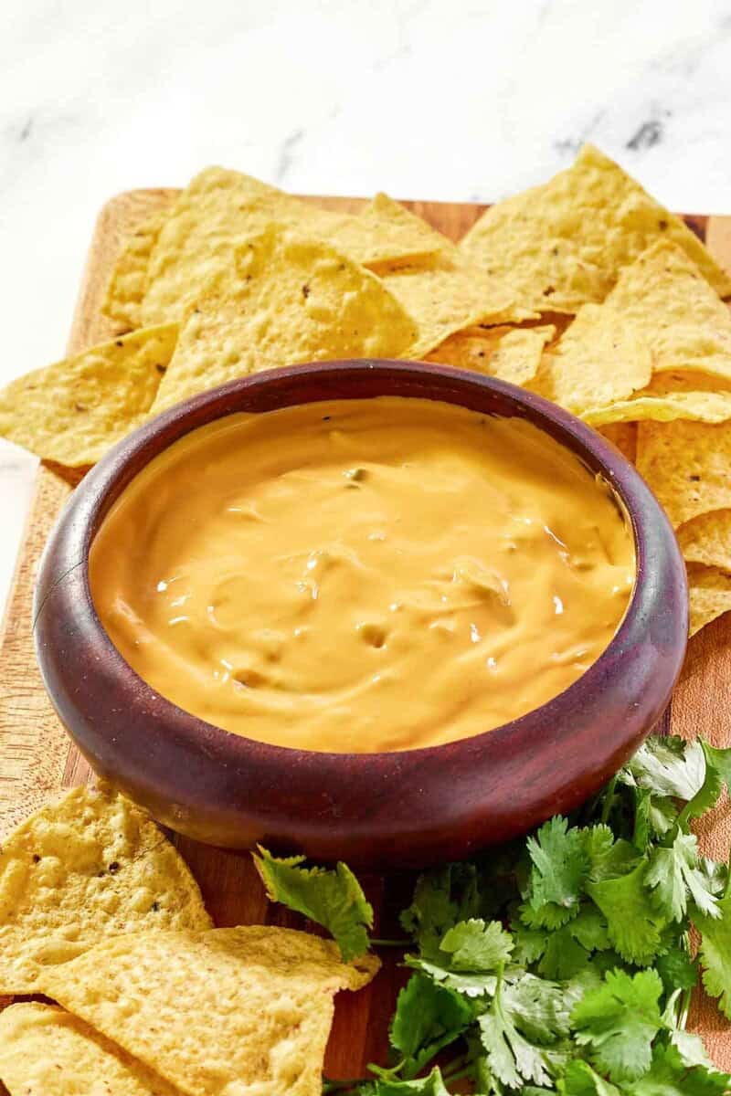 Green chile queso dip, tortilla chips, and fresh cilantro on a platter.