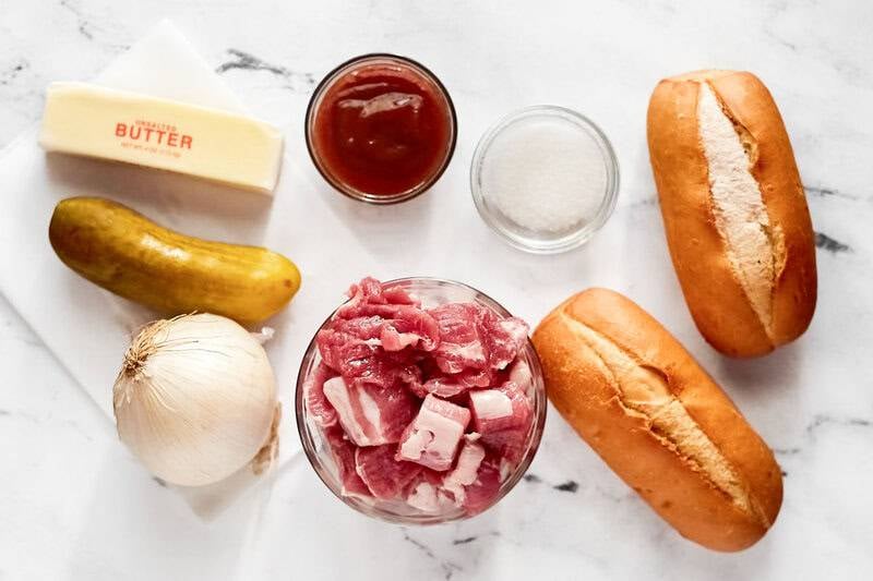 cubed pork, hoagie rolls, a pickle, an onion, butter, and barbecue sauce.