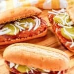 Homemade McDonald's McRib sandwiches and a kitchen towel on a wood board.