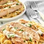 Homemade Olive Garden chicken alfredo on two plates and two forks on a napkin.