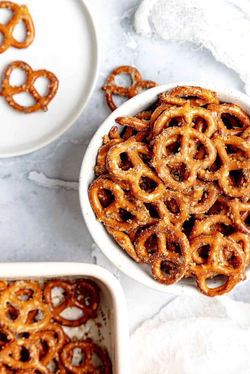 Homemade ranch pretzels in a small bowl, on a plate, and in a baking dish.