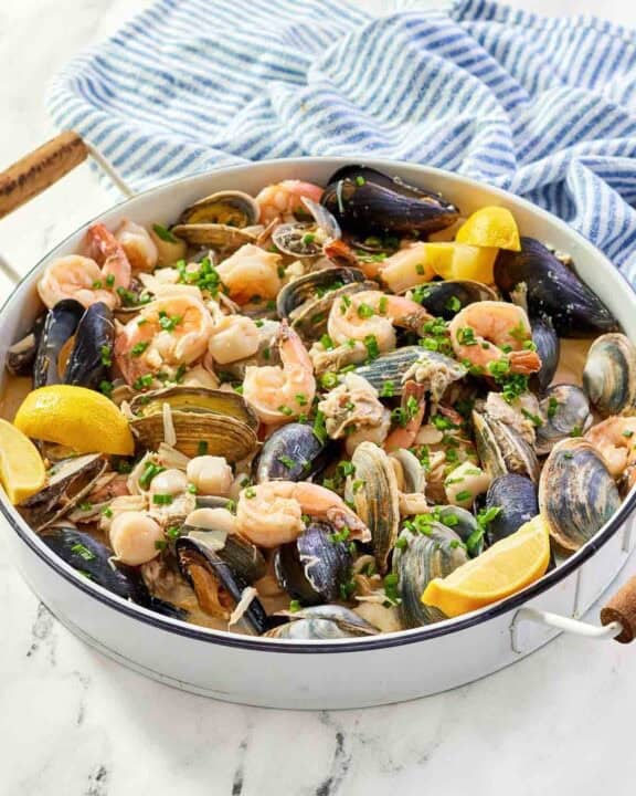 Copycat Silver Legacy Casino seafood pan roast and a kitchen towel on a marble surface.