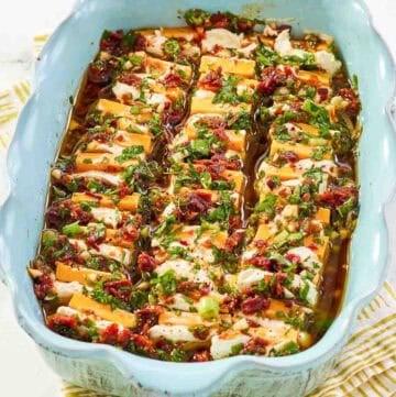 Sliced cheeses in a sundried tomato herb marinade served for an appetizer.