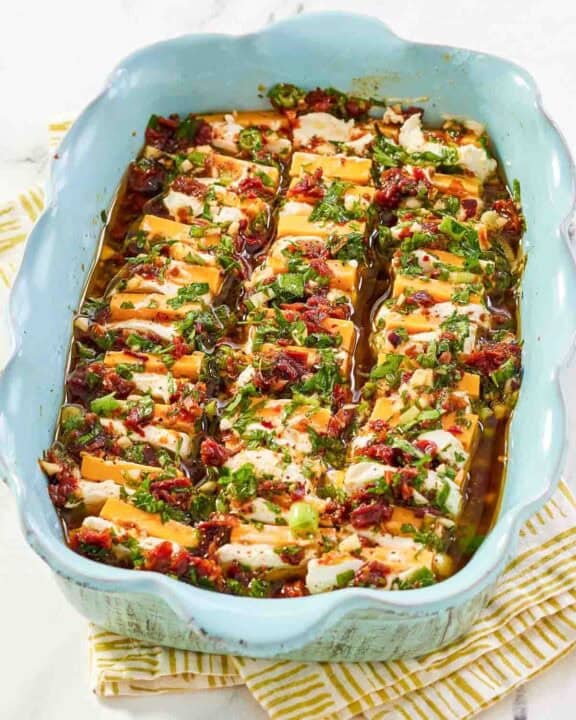 Sliced cheeses in a sundried tomato herb marinade served for an appetizer.