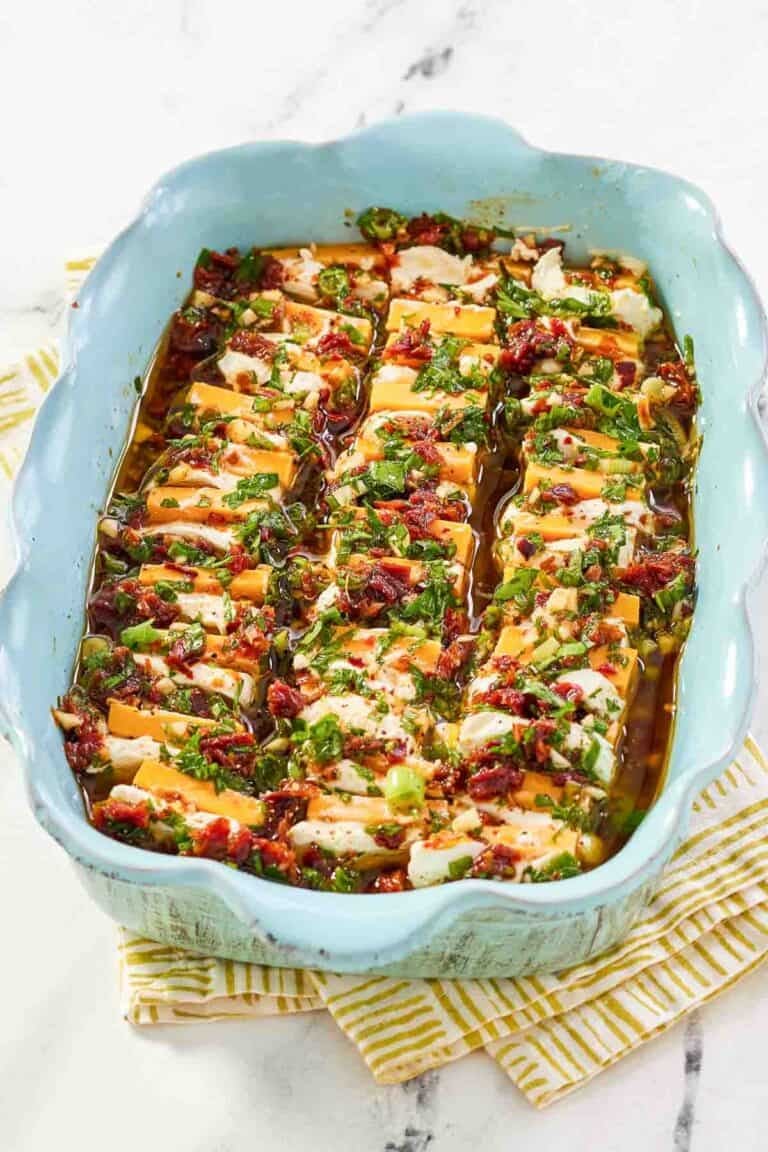 Sliced cheeses in a sundried tomato herb marinade served for an appetizer.