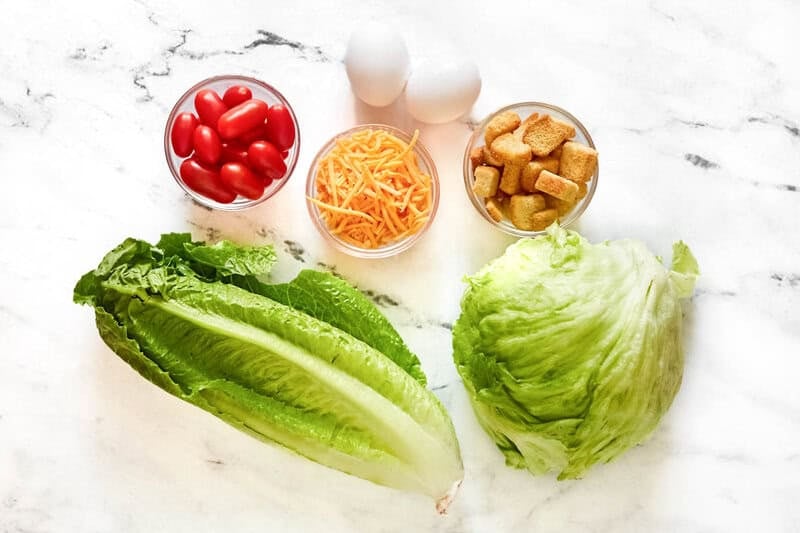 Lettuce, tomatoes, eggs, shredded cheese, and croutons.