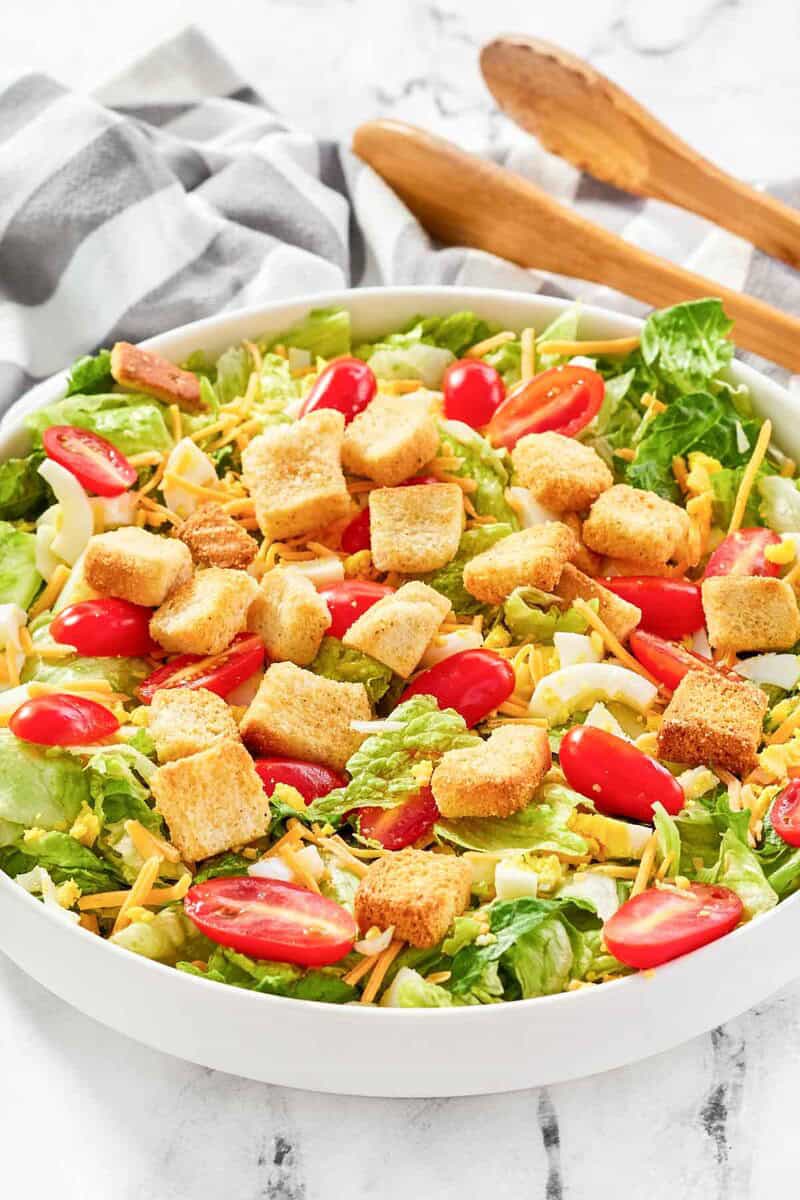 A salad with tomatoes, boiled eggs, cheese, and croutons.