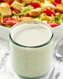 Copycat Texas Roadhouse ranch dressing in a jar and a salad behind it.