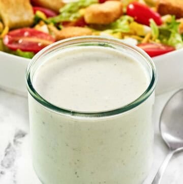 Copycat Texas Roadhouse ranch dressing in a jar and a salad behind it.