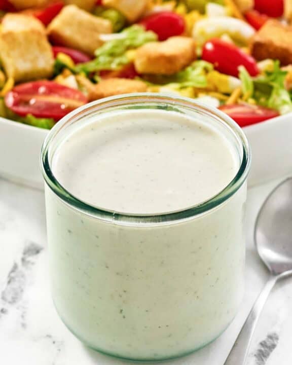 Copycat Texas Roadhouse ranch dressing in a jar and a salad behind it.
