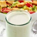 Homemade Texas Roadhouse ranch dressing in a jar and a salad behind it.