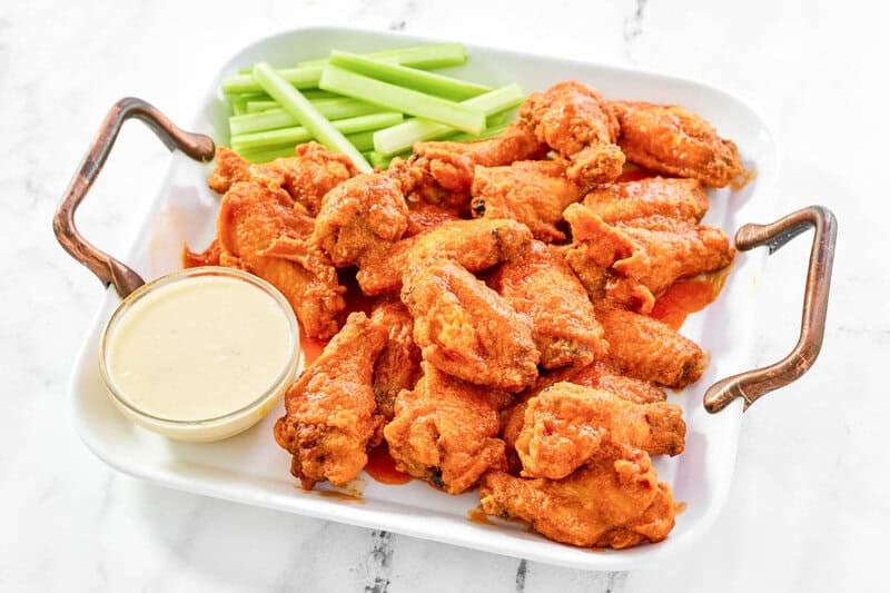 A platter of crispy garlic Buffalo wings with celery and dip