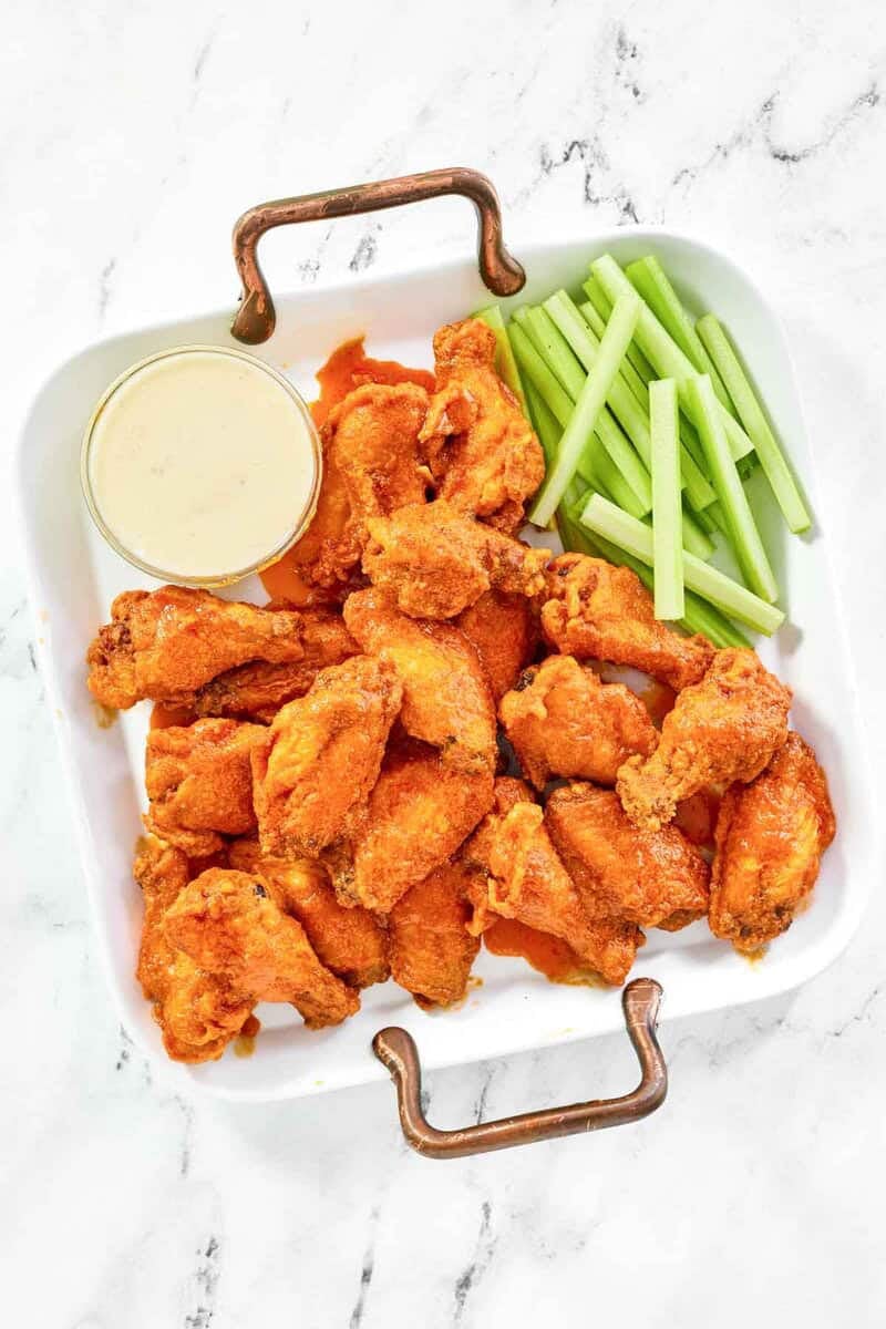Copycat Wings and Things garlic buffalo wings, celery sticks, and blue cheese dressing on a platter.