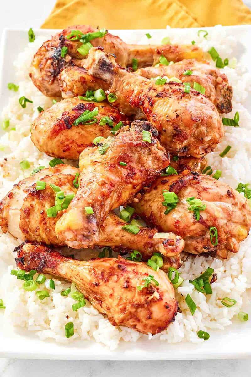 Baked and glazed chicken drumsticks served on top of rice and garnished with green onions.