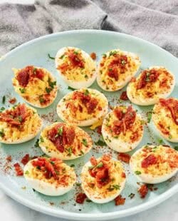 Deviled eggs topped with candied bacon bits and paprika.
