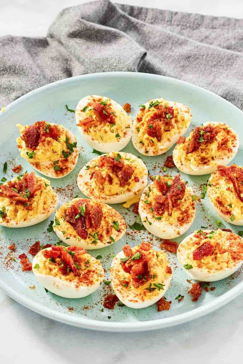 Deviled eggs topped with candied bacon bits and paprika.