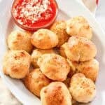 Cheesy garlic bread balls served with marinara on a platter.