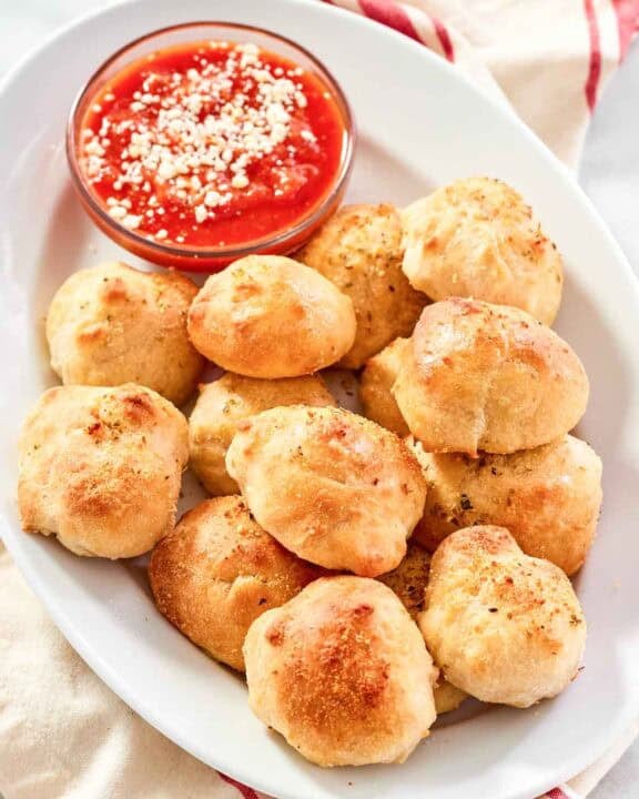 Cheesy garlic bread balls served with marinara on a platter.
