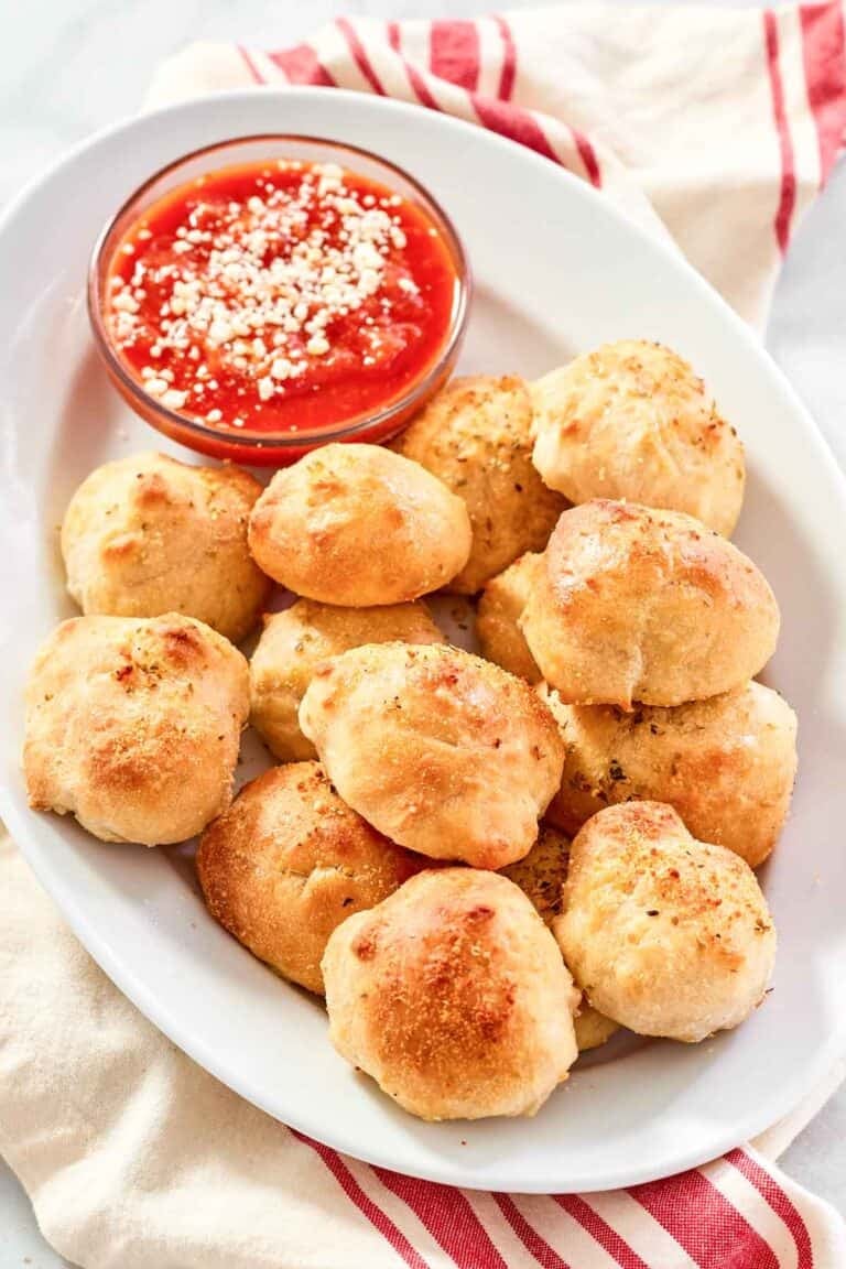 Cheesy garlic bread balls served with marinara on a platter.