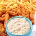 Creamy homemade tartar sauce on a plate with crispy fish sticks and French fries.