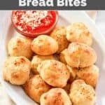 Cheesy bread bites and a cup of marinara sauce on a platter.