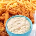 A fish sticks platter with fries and tartar sauce.