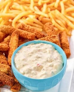 A fish sticks platter with fries and tartar sauce.
