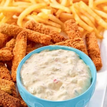 A fish sticks platter with fries and tartar sauce.
