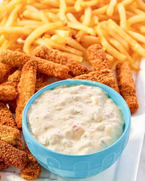 A fish sticks platter with fries and tartar sauce.