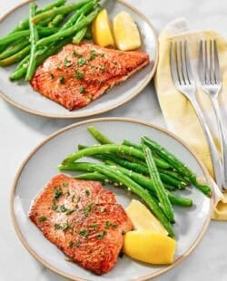 Atlantic salmon with lemon butter served with lemon wedges and green beans.