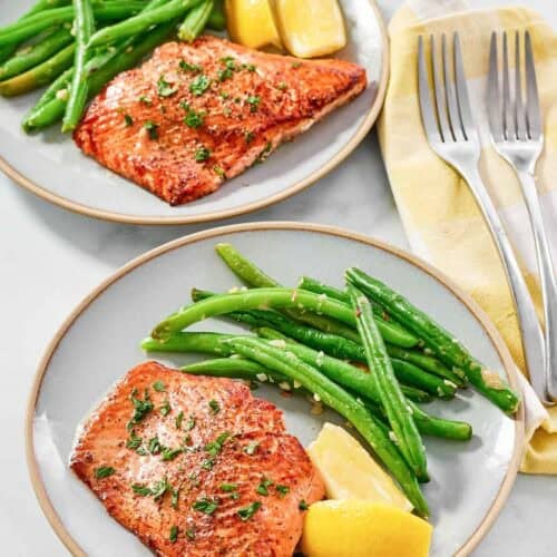 Atlantic salmon with lemon butter served with lemon wedges and green beans.