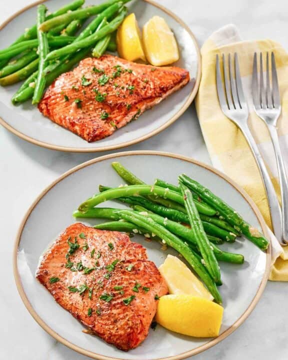 Atlantic salmon with lemon butter served with lemon wedges and green beans.