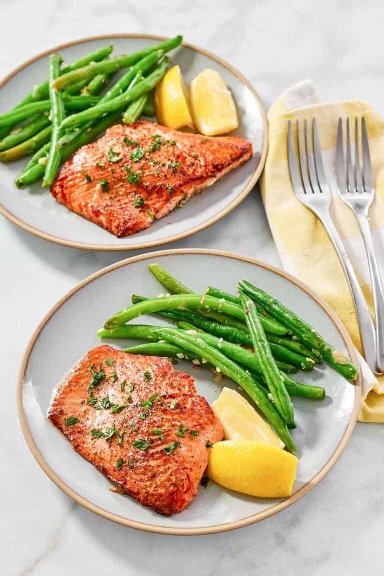Atlantic salmon with lemon butter served with lemon wedges and green beans.